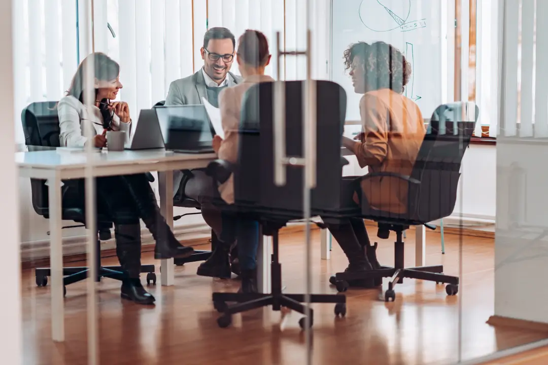 a group of people sitting at a table with laptops